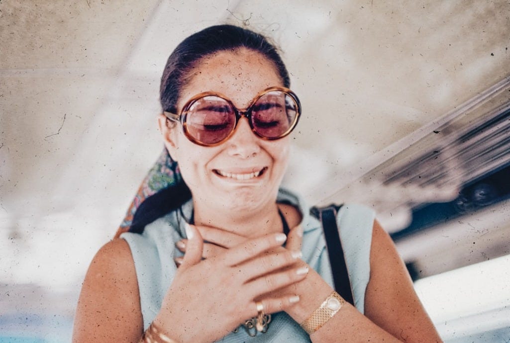 A woman wearing sunglasses is smiling for the camera