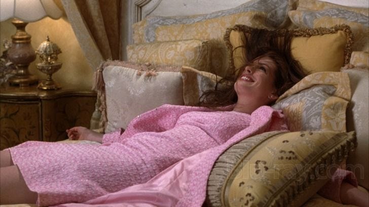 This may contain: a woman laying on top of a bed in a pink dress