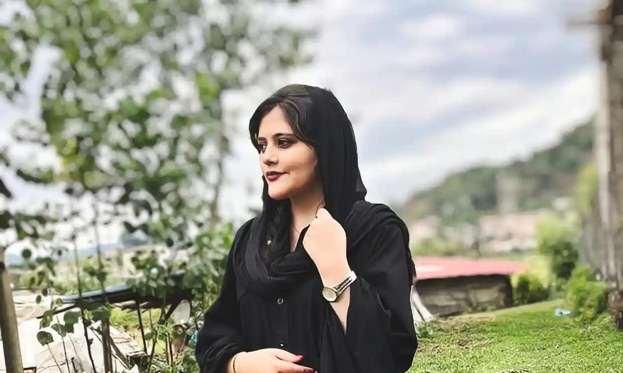 An image of 22-year-old Kurdish woman Mahsa Amini who died late last week in the custody of Iranian morality police. In the photo, where we see Amini from the waist up, she is wearing all black, most of her hair covered, as she looks into the distance.