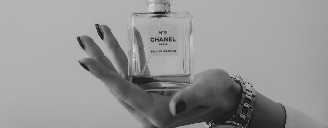 grayscale photo of person holding clear glass bottle