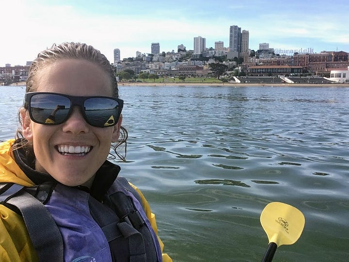 A rescue kayaker on San Francisco Bay during the Escape from Alcatraz triathlon, with the Golden Gate Bridge in the distance.