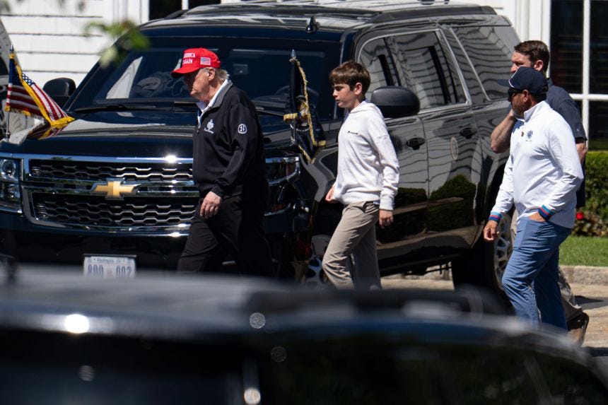 President Donald Trump walks with his grandchild Spencer Trump after golfing at Trump National Golf Club in Sterling, Virginia, on Saturday.