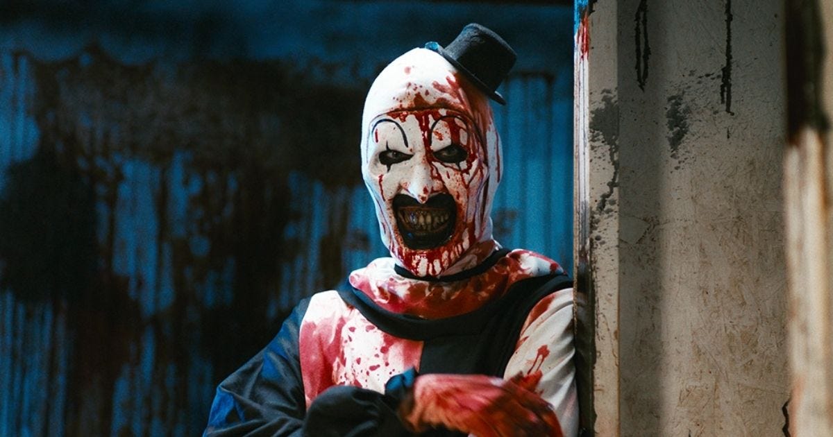 Art the Clown stands drenched in blood with a blank, eerie expression — a chilling snapshot of Terrifier’s obsession with gore over meaning.