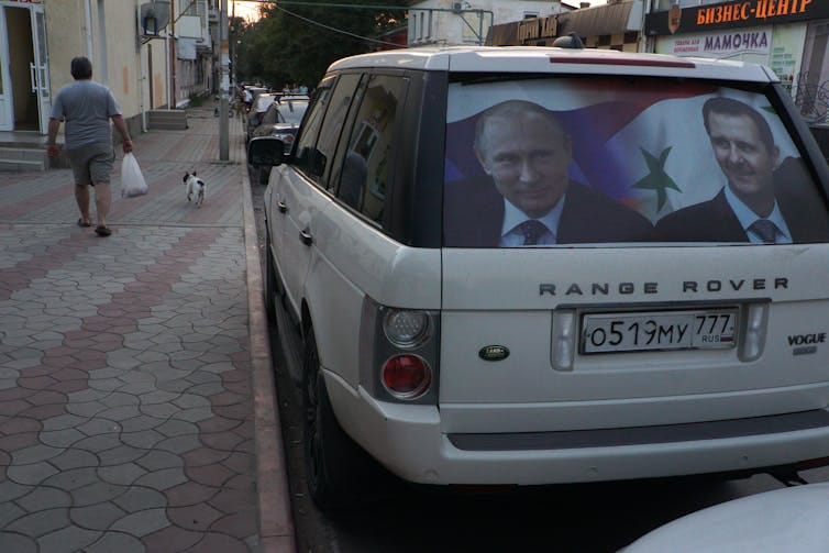 A car has a picture of two men in the rear window. A car has a picture of two men in the rear window.