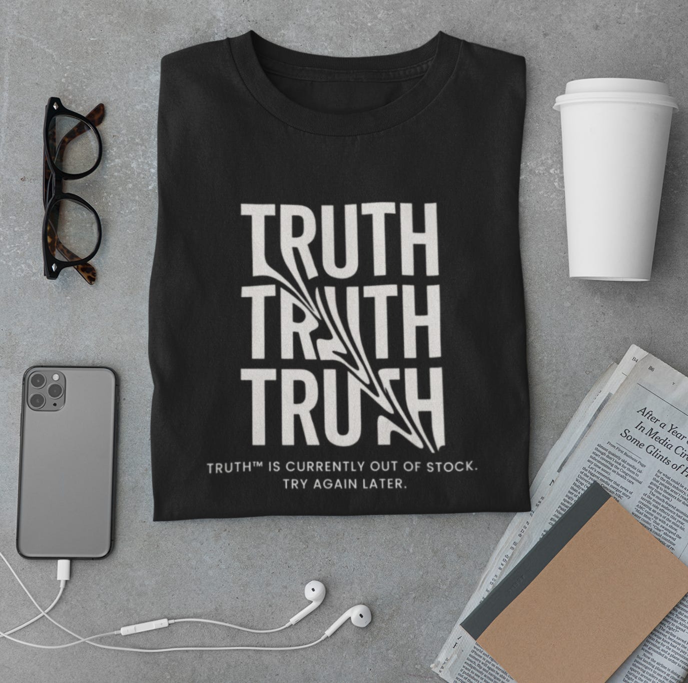 Black folded t-shirt with bold white typography repeating the word “TRUTH” three times, the middle version distorted by a glitch-like design. Below it reads: “TRUTH™ is currently out of stock. Try again later.” Shirt is styled flat lay on concrete with glasses, smartphone, earbuds, and coffee cup—evoking a minimalist, modern aesthetic with a dystopian edge.