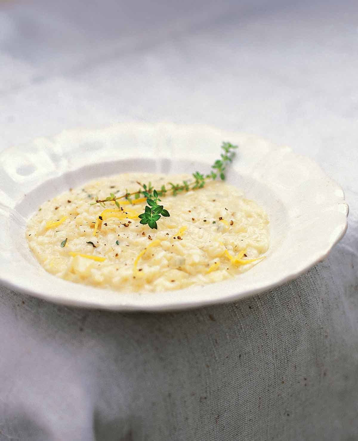 A shallow bowl of rich, creamy Lemon & Thyme Risotto finished with a silky egg yolk and Parmesan emulsion, garnished with fresh thyme sprigs.