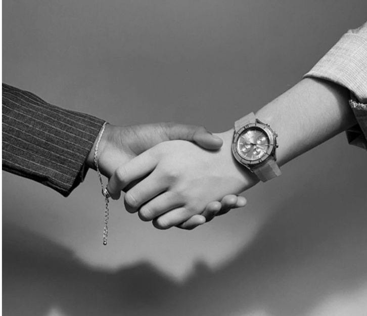 This may contain: two people are holding hands while wearing watch and bracelets on their wrist, in black and white