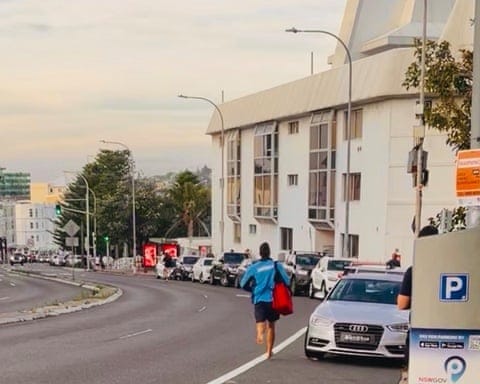 Waverley Council lifeguard Jackson Doolan is captured running towards Bondi beach holding a red kit bag in a viral photo