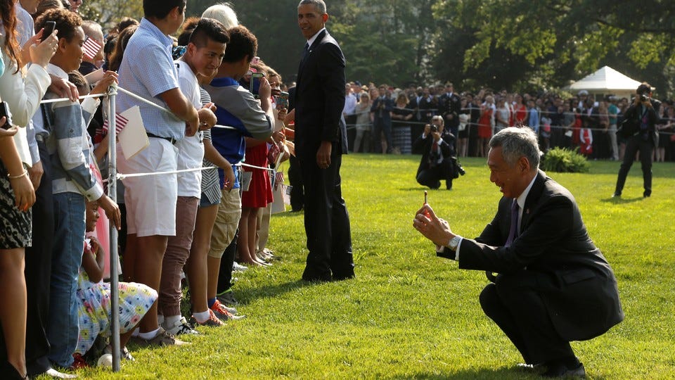 A man squats to take photos of people