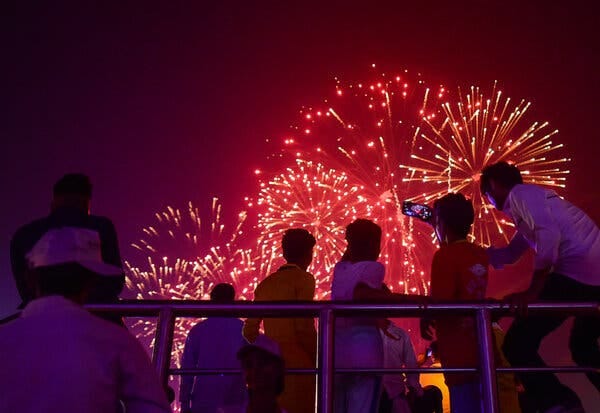 People look up as red fireworks illuminate the night sky.