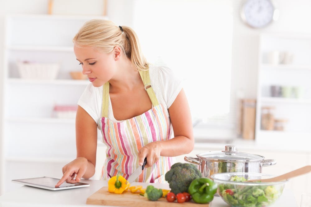 Blonde woman using a tablet computer to cook in her kitchen Blonde woman using a tablet computer to cook in her kitchen