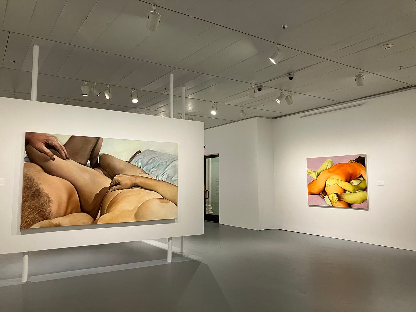 photograph of a museum gallery with several large bright canvasses of naked bodies on display photograph of a museum gallery with several large bright canvasses of naked bodies on display