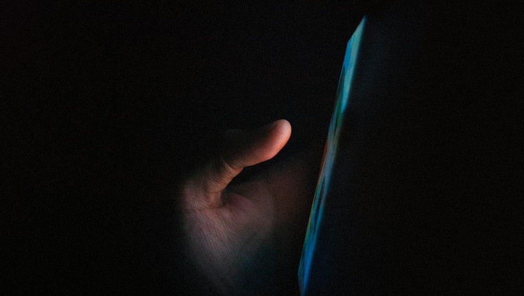 person holding blue light in dark room