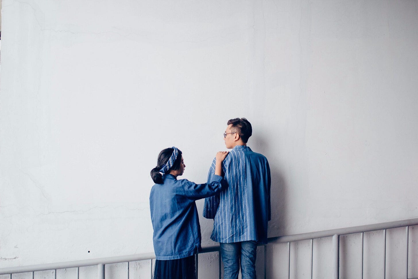 A man glances back at a woman, who places her hand on his shoulder.