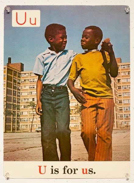 This may contain: two young boys standing next to each other in front of tall buildings and the words u is for us