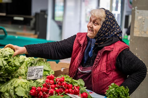 Această galerie se oprește asupra oamenilor din piață: vânzători, legumicultori, femei și bărbați pentru care taraba nu este doar loc de lucru, ci rezultatul unei munci duse luni întregi. Ridurile, privirile, gesturile și răbdarea lor spun o poveste despre efort, continuitate și legătura directă dintre pământ și oraș.