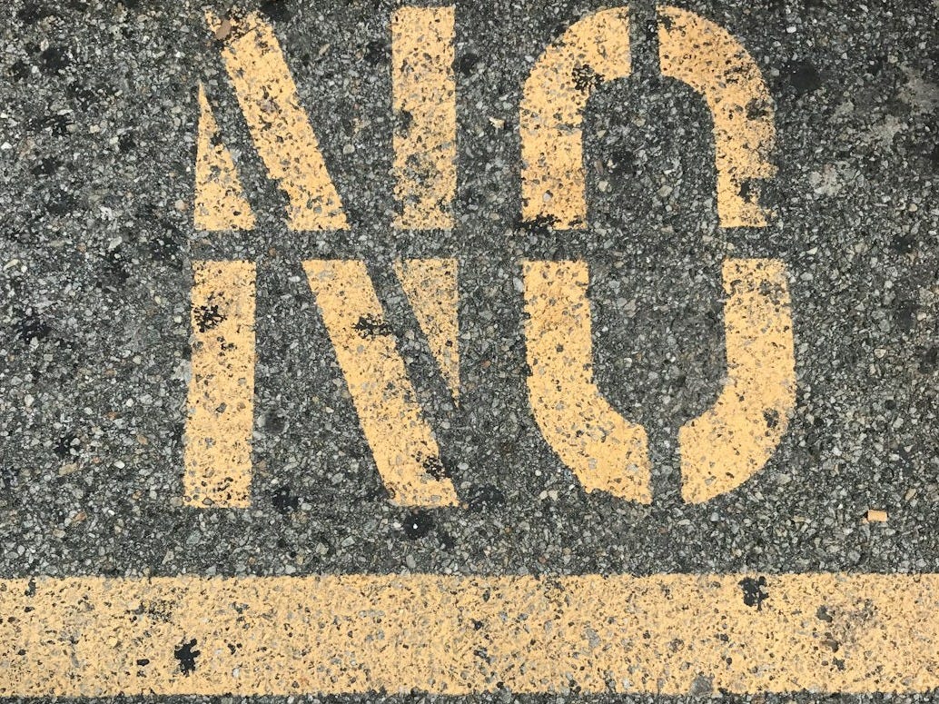 person wearing black leather shoes standing on gray concrete pavement with yellow and black i love