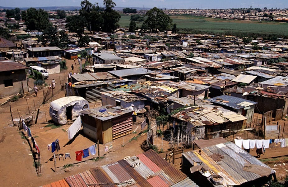 Aerial view of crowded settlement of small structures, with unpaved spaces between them Aerial view of crowded settlement of small structures, with unpaved spaces between them