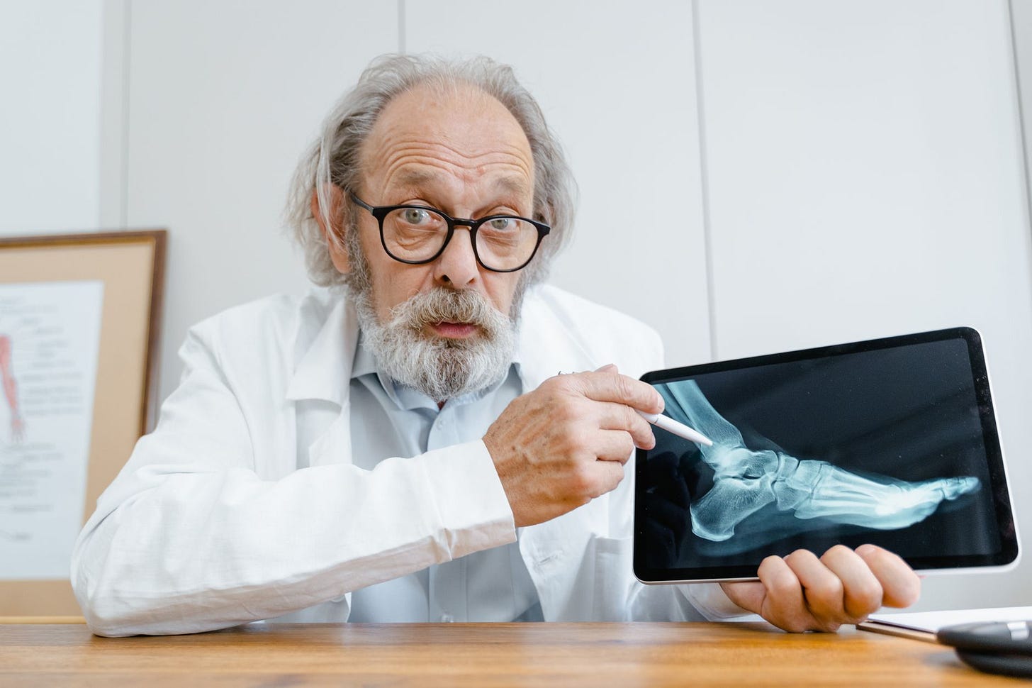 Photo by Tima Miroshnichenko on Pexels Elderly doctor examining an X-ray on a digital tablet in a clinical setting. (stock photo)