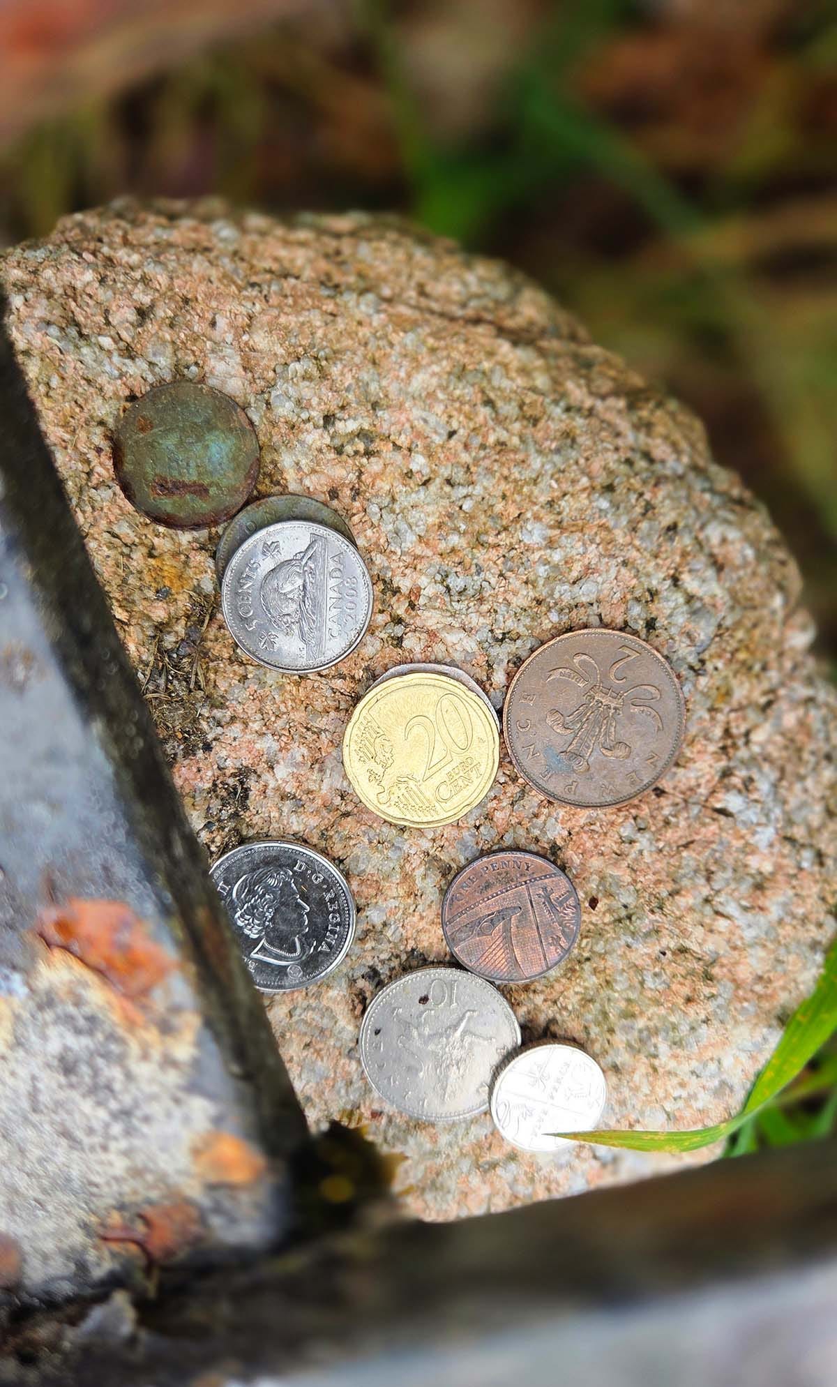 Coins from everywhere atop a homing stone on Seath Mor's grave. 