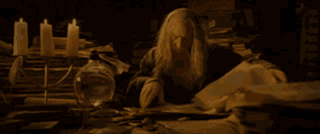 a man with long white hair sits at a table with candles