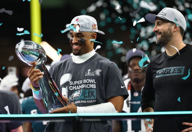 Philadelphia Eagles quarterback Jalen Hurts (1) holds the Vince Lombardi Trophy as Philadelphia Eagles head coach Nick Sirianni looks on after defeating the Kansas City Chiefs in Super Bowl LIX at Caesars Superdome.