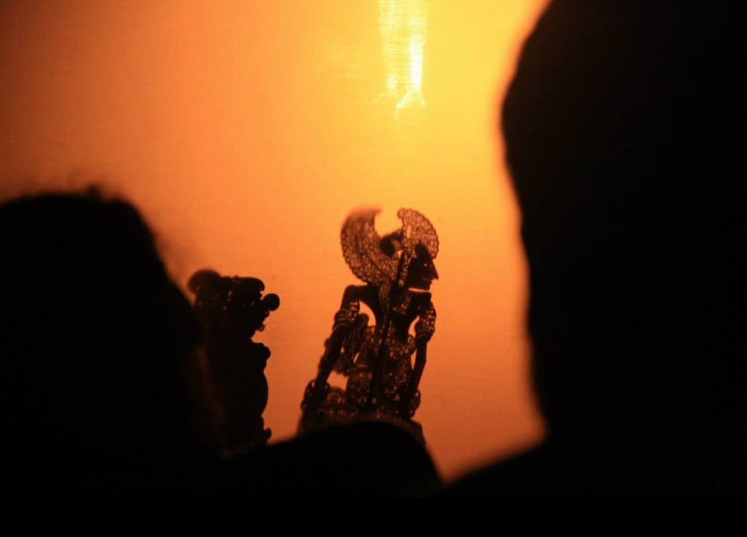 Silhouette of a complex papercut puppet against a orange-yellow background. Silhouette of a complex papercut puppet against a orange-yellow background.