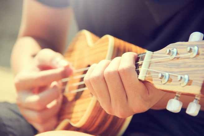 person playing brown ukulele person playing brown ukulele