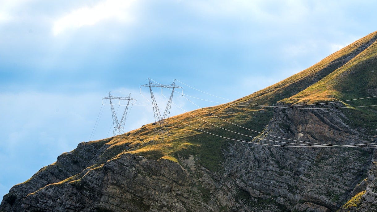 Photo depicts power pylons in the mountains