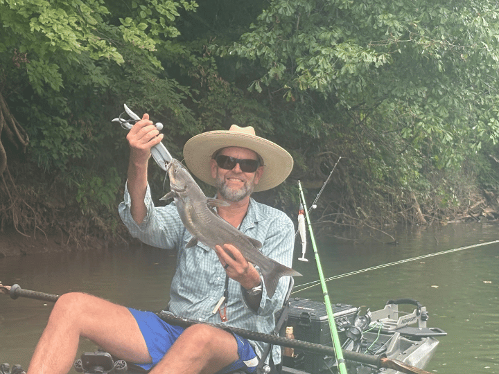 A picture of a man in a kayak holding up a catfish. A picture of a man in a kayak holding up a catfish.