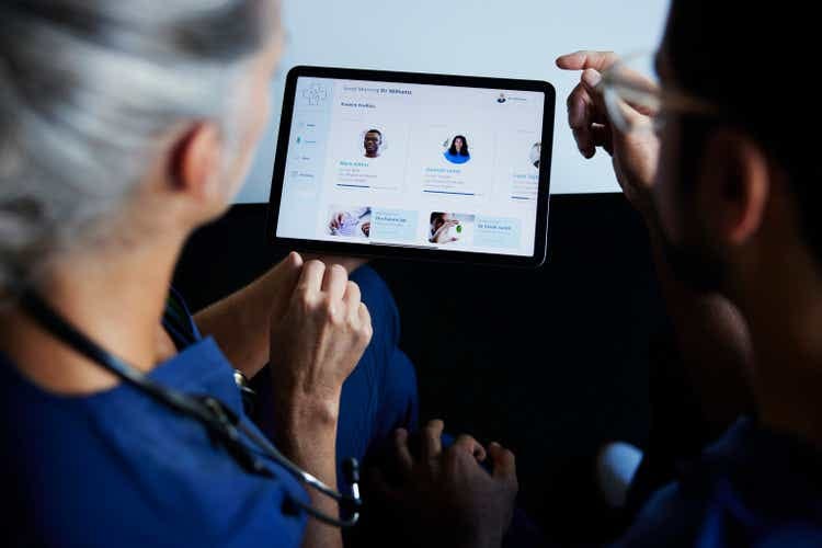 Two doctors looking at patient data on  digital tablet