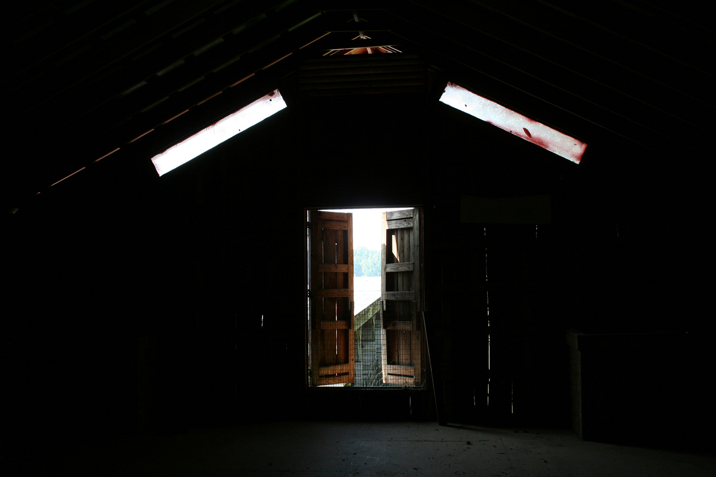 Inside a dark barn with a door opened in the distance. Inside a dark barn with a door opened in the distance.