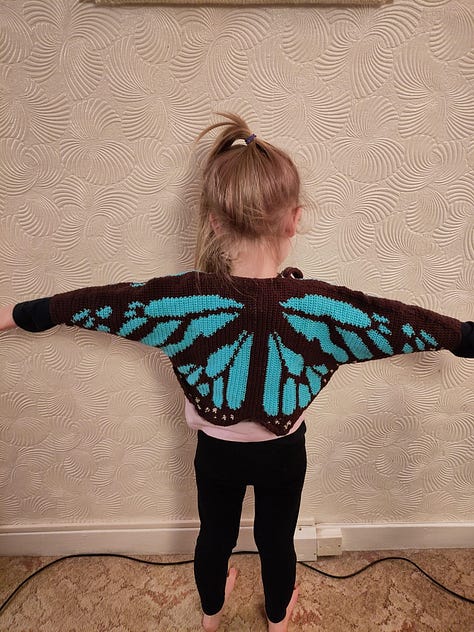 9 pictures of different fiber arts projects including a knit tapestry that says "Protect Trans Youth, a crochet tapestry of a wee ghost, a crochet blanket, a table runner, needle felted keychains, a butterfly cardigan for a little kid, and a blue and white striped cardigan for an adult.