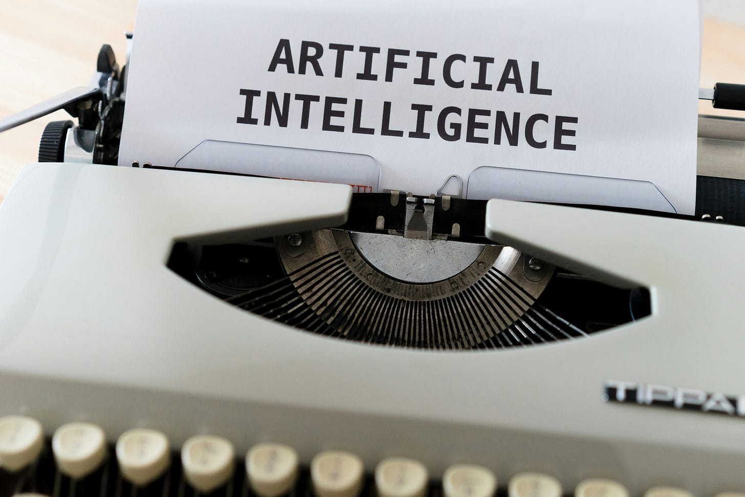 The words "Artificial Intelligence" are printed on a paper sticking out of a typewriter.