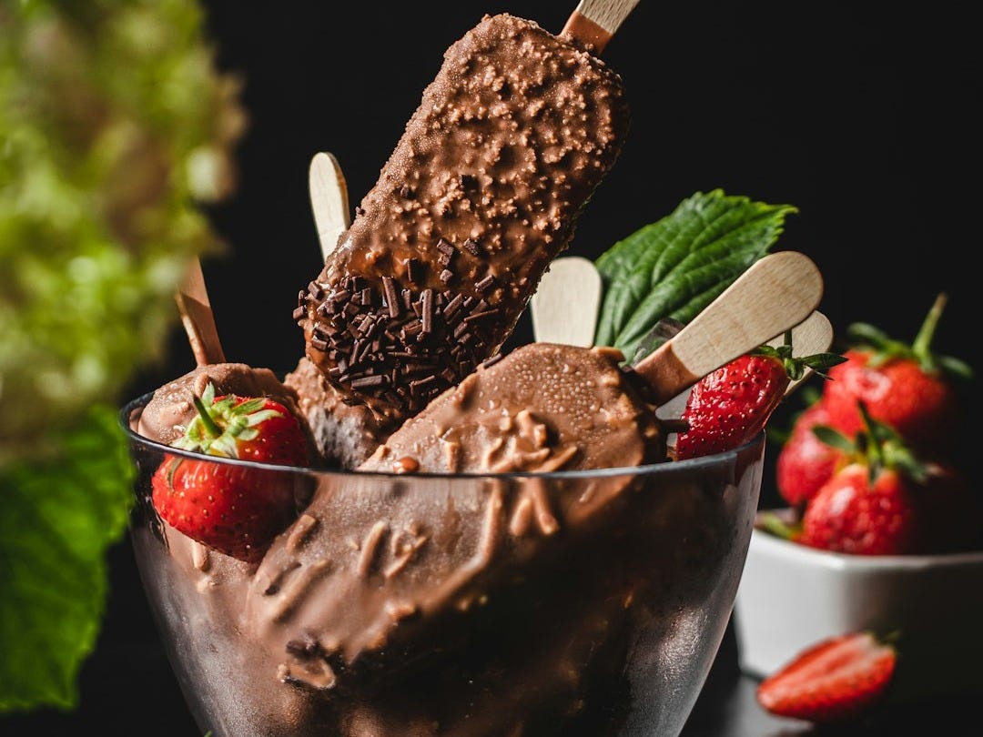 person holding ice cream with strawberry on top