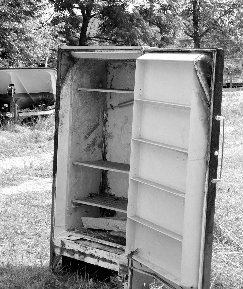Old rusty refrigerator standing outdoors in grass Old rusty refrigerator standing outdoors in grass