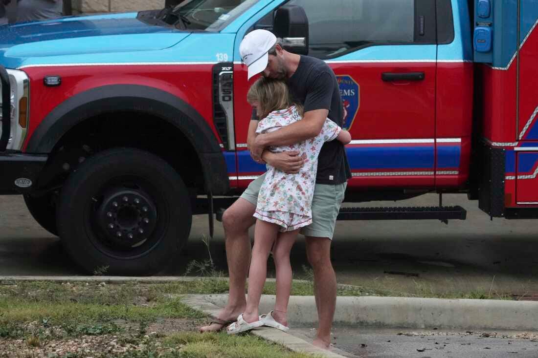 People are reunited at a reunification center after flash flooding hit the area, Friday, July 4, 2025, in Ingram, Texas.