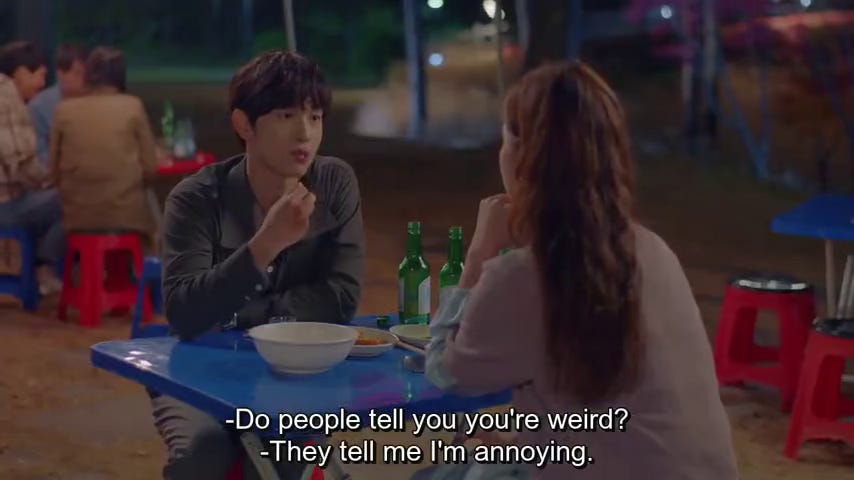 a man an woman converse over food. she asks him if people tell him he's weird, and he responds that people describe him as annoying.