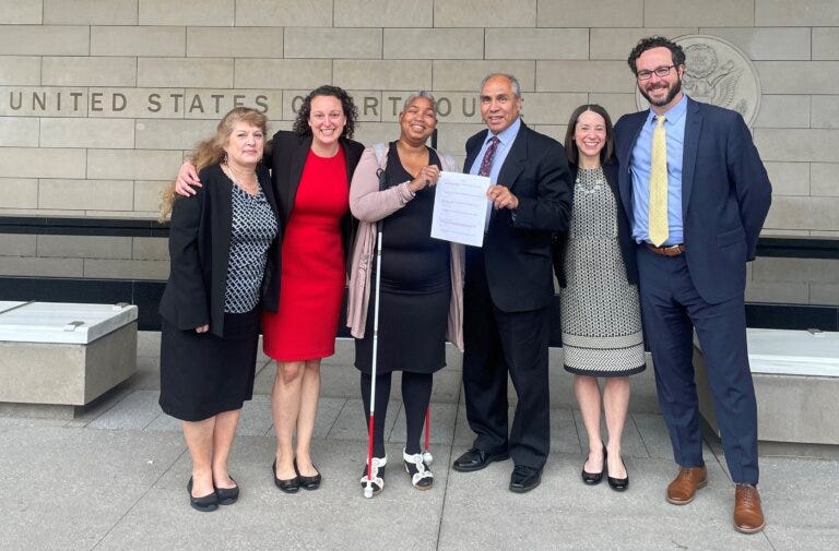 Two blind students and their legal team standing in front of a courthouse