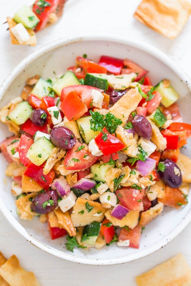 A bowl of chopped greek salad with pita chips. A bowl of chopped greek salad with pita chips.