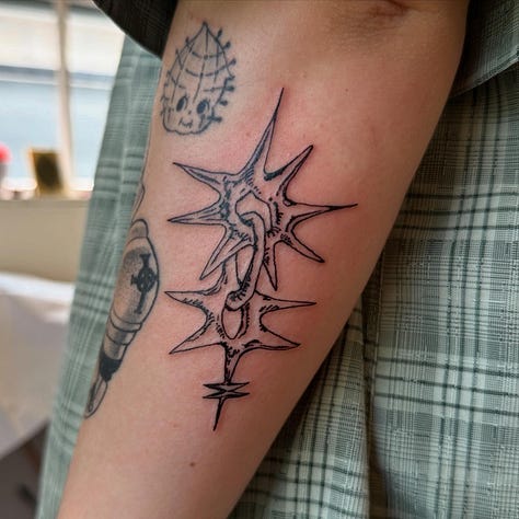 9 photos of tattoos i did this month. from top left to bottom right: a stuffed animal from item label called a peepy, a spiky chain link, a dog dragon, a starry sacred heart, a little guy holding a leaf, another chainlink with a dark black spiky background, another chain link, a brick with leaves growing out of it, and a spiral star on someones elbow (ouch!)
