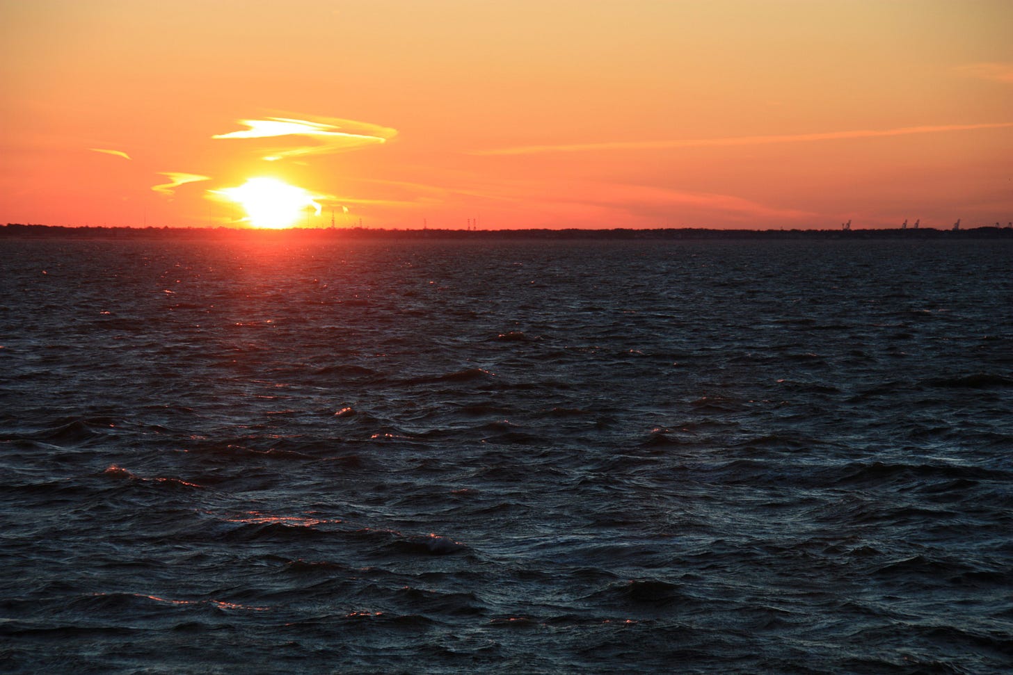 A dark ocean and a burning sun in an orange sky A dark ocean and a burning sun in an orange sky