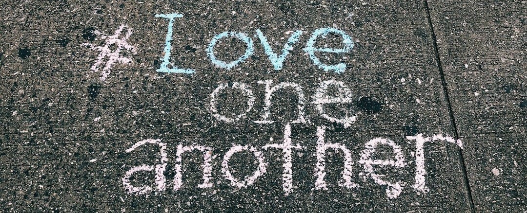 love one another chalk written on concrete floor