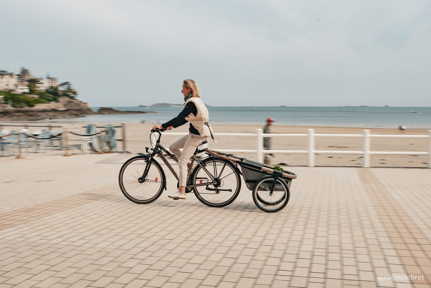 Femme le long de le plage avec un velo monte avec une remorque