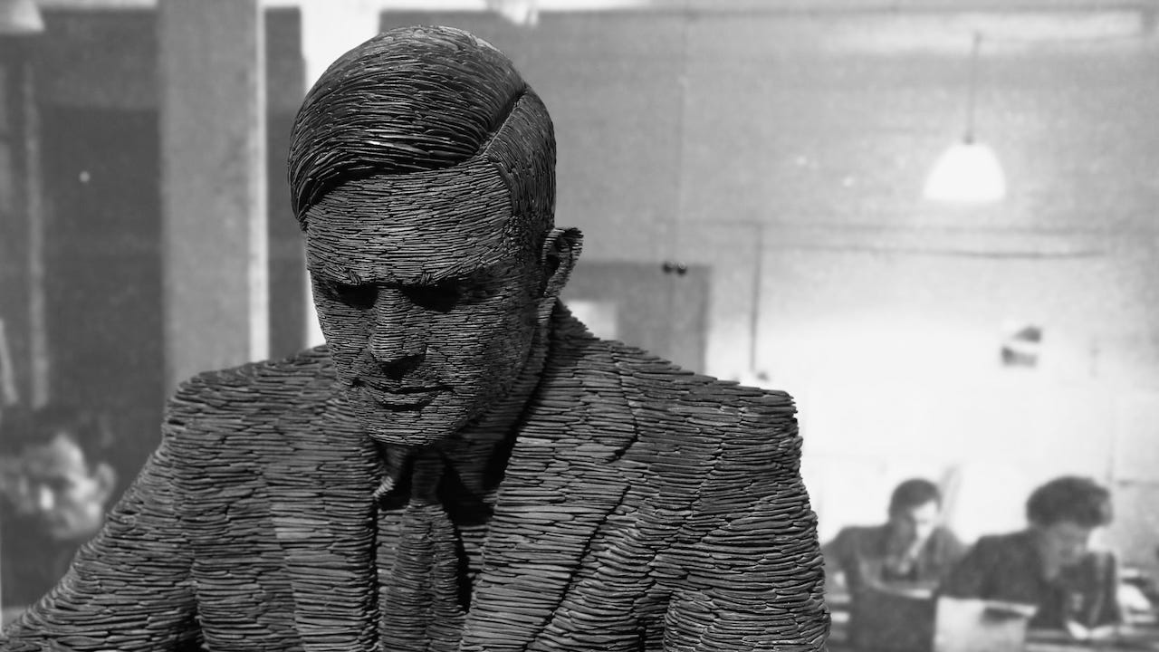 Black-and-white photograph of a lifelike sculpture of a man in a suit, composed of many thin, stacked horizontal layers, looking downward as if reading or concentrating; blurred figures seated at desks appear in the background, suggesting an office setting. Black-and-white photograph of a lifelike sculpture of a man in a suit, composed of many thin, stacked horizontal layers, looking downward as if reading or concentrating; blurred figures seated at desks appear in the background, suggesting an office setting.