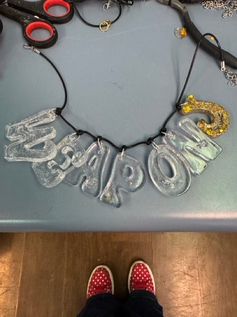 Images show Weapon S and J necklaces plus a gift wrapped box