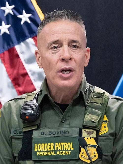 official portrait of Greg Bovino, Border Patrol; his id is on his quasi military uniform. an american flag is in the background. Bovino has a horribe, fash-adjacent hair cut and his face looks like it is trying to crawl off his skull to get away from the evil official portrait of Greg Bovino, Border Patrol; his id is on his quasi military uniform. an american flag is in the background. Bovino has a horribe, fash-adjacent hair cut and his face looks like it is trying to crawl off his skull to get away from the evil