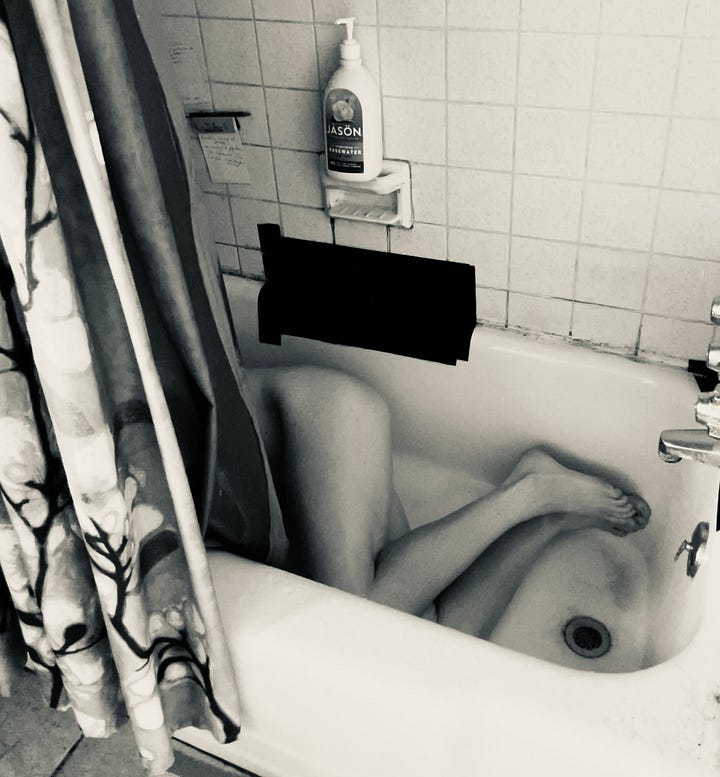 A series of four black and white self-portraits of a person sitting in a bathtub alone. They are covering themself, curled into a ball. The sense is solitary and lonely.