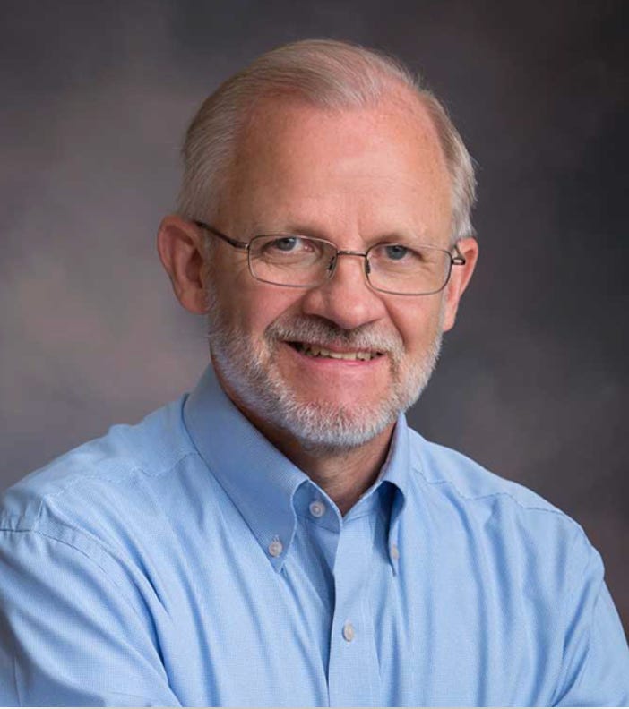 Portrait of John Miller, an older man with white hair, glasses, and a light blue shirt. Portrait of John Miller, an older man with white hair, glasses, and a light blue shirt.