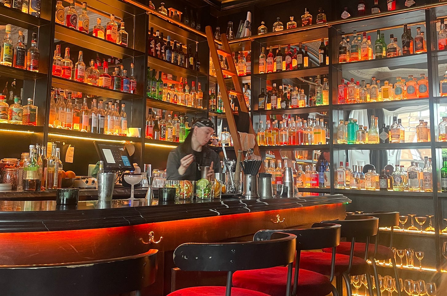 A bar person is mixing a cocktail at a very beautiful and glowing cocktail bar